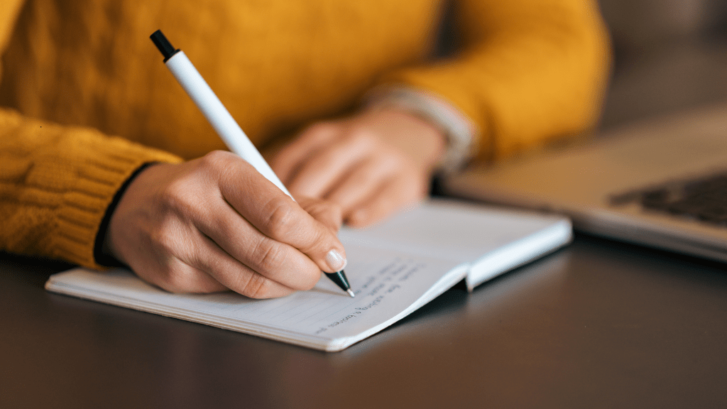mujer escribiendo en un cuaderno sus pensamientos cuestionándolos con la técnica de Byron Katie The Work, para fluir mejor en su vida y en su emprendimiento